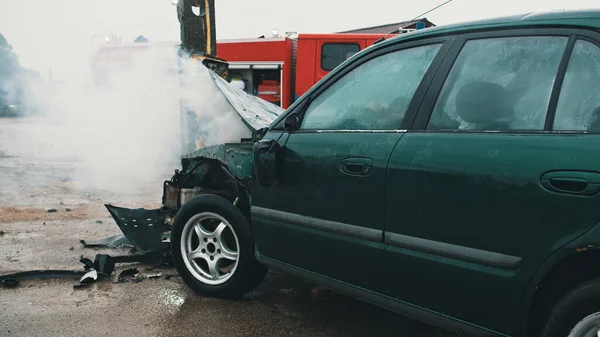 Крупным планом дым от разбитой машины с пожарной машиной на заднем плане. Автокатастрофа — стоковое фото