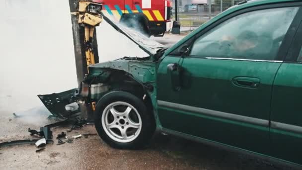 De perto, fumo de um carro destruído com um carro de bombeiros ao fundo. Acidente de carro — Vídeo de Stock