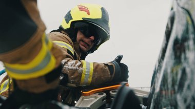 İtfaiyeciler kapana kısılmış kurbanı arabadan çıkarmak için hayat pençesi kullanıyorlar.