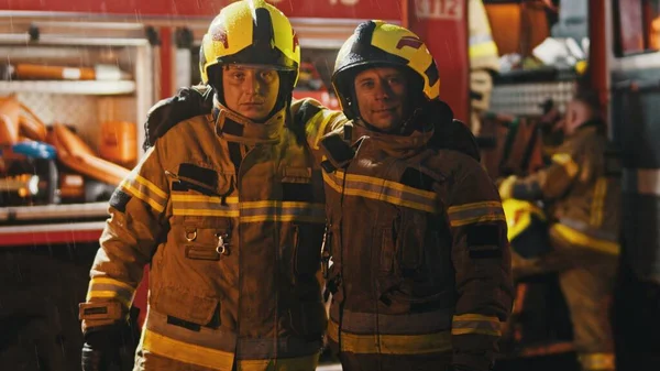 Retrato de dos bomberos delante del camión de bomberos después de apagar el fuego —  Fotos de Stock