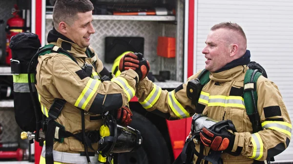 Zwei Feuerwehrleute beim Händeschütteln nach erfolgreicher Brandschutzübung — Stockfoto