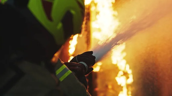 Brandman släcker elden med slangen. Brinnande hus brandövning — Stockfoto