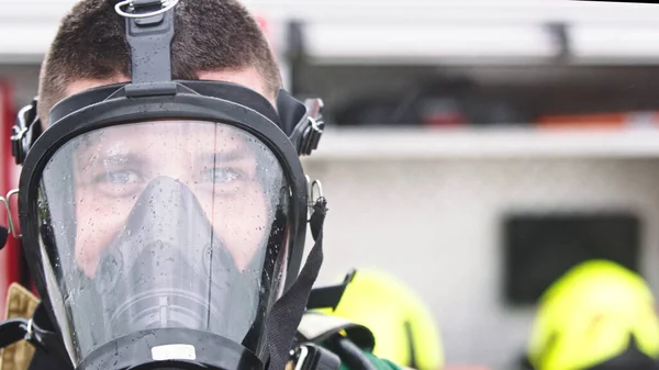 Close-up, retrato de bombeiro usando máscara de gás na frente do carro de bombeiros — Fotografia de Stock