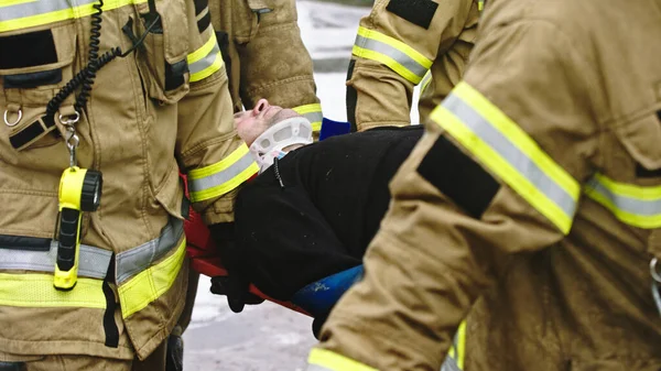 Feuerwehrleute heben verletzten Mann auf. Rettung nach Autounfall — Stockfoto