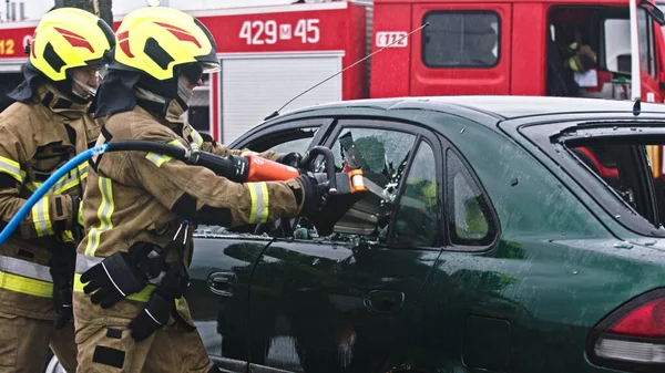 Firefighter beraking glass using jaws of life to extricate trapped victim from the car Stock Image