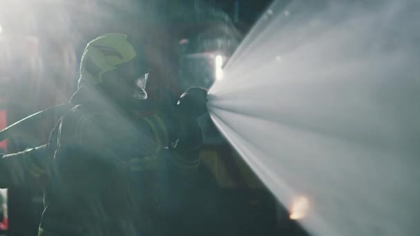 消防士は夜間にホースで噴霧し、火災を消火. — ストック動画