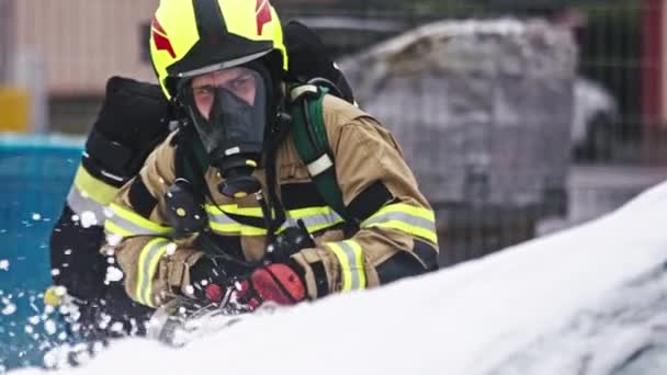 Пожарный тушит огонь из горящей машины с помощью пены — стоковое видео