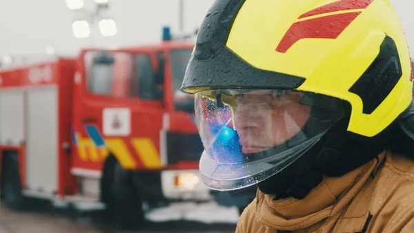 Портрет молодого пожежника в повній уніформі перед вогневим двигуном — стокове фото