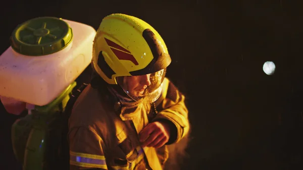 Pemadam kebakaran dengan tabung di punggungnya di malam hari. Latihan kebakaran — Stok Foto