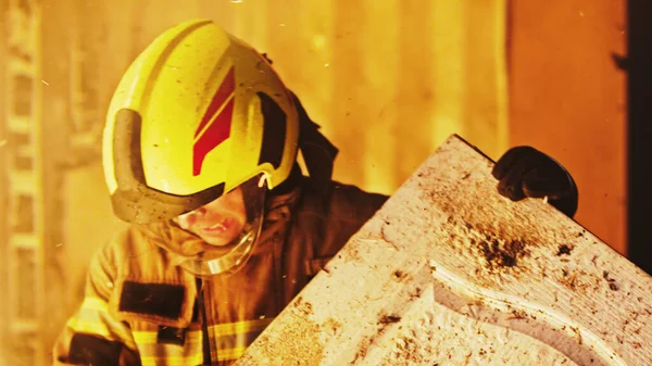 Bombeiro ajudando a extinguir fogo em casa em chamas. — Fotografia de Stock