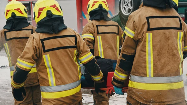 Bomberos que transportan heridos. Taladro contra incendios —  Fotos de Stock