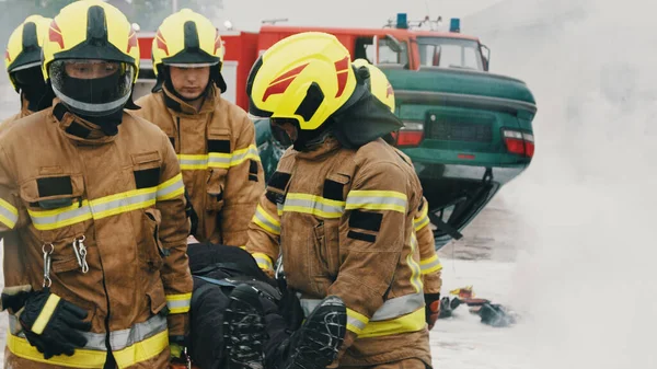 Brandmän som bär en skadad person. Brandövning — Stockfoto