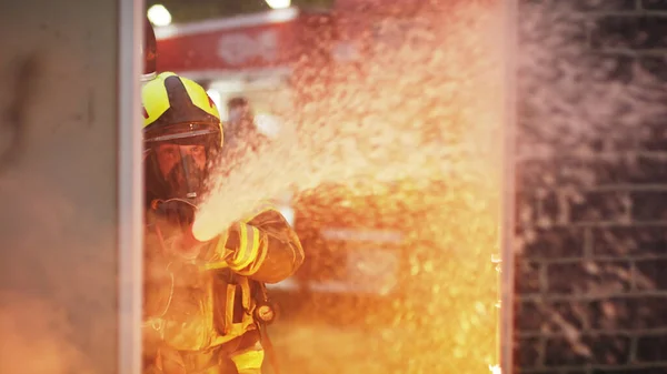 Pompier éteindre le feu avec le tuyau. Perceuse incendie maison en feu — Photo