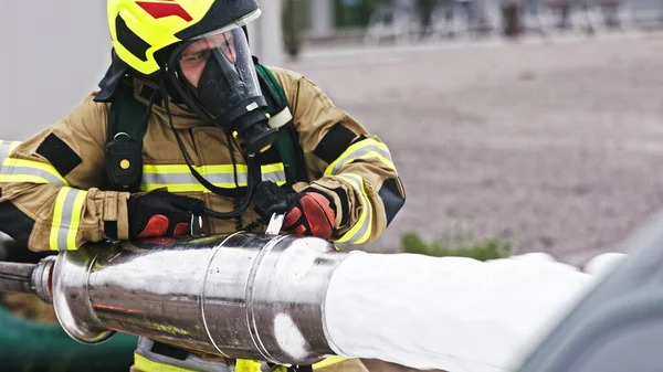 Pompiere spegnere una macchina in fiamme con schiuma — Foto Stock