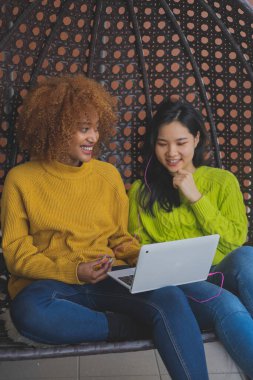 İki genç kadın dedikodu yapıyor ve sosyal ağlara takılıyor. Çok ırklı dostluk