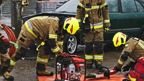 Firefighters preparing the hose for hidraulic cutter on the car crash scene — Φωτογραφία Αρχείου