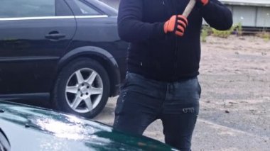 Kızgın adam büyük çekiçle araba kırıyor. Terör ve vandalizm kavramı