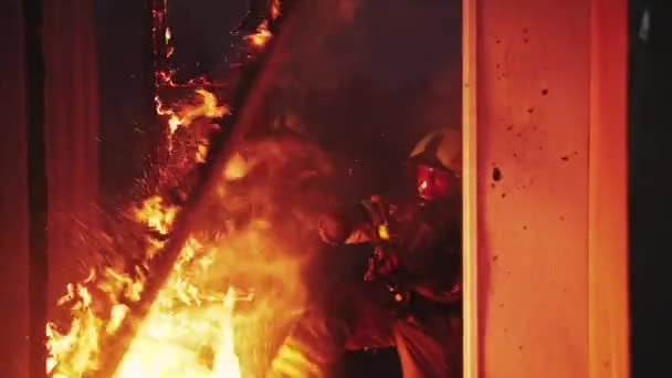 Bombero ayudando a extinguir el fuego en la casa en llamas. — Vídeos de Stock