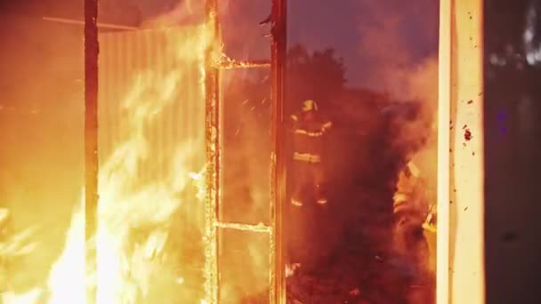 Firefighter helping to extinguish fire in burning house. — Stock Video