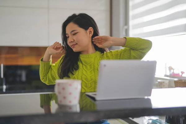 Joven mujer asiática estirándose delante de la computadora portátil en la mañana en su apartamento — Foto de Stock