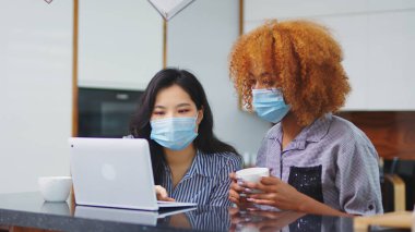 Yeni normal. Proje üzerinde tıbbi maskeli kadın meslektaşlar koruyucu tedbirlerle çalışıyorlar