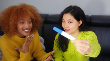 Pozitif hamilelik testine bakan mutlu iki genç kadın. Gelecekteki anneyi destekleyen en iyi arkadaş.