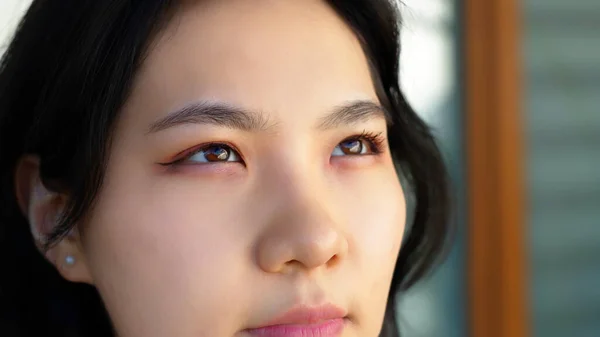 Portrait de jeune femme asiatique heureuse avec fard à paupières rose et rouge à lèvres appréciant le matin sur le balcon. Gros plan — Photo