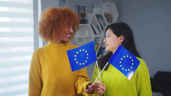 Amitié multiraciale et égalité. Femme afro-américaine et asiatique tenant le drapeau de l'Union européenne. Programme d'échange d'étudiants — Photo