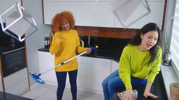 Two young women having fun while doing house cleaning. Multiracial friendship or relationship — Stock Photo, Image