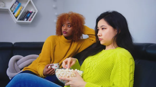 Çok ırklı dostluk. Afgan Amerikalı siyah ve Asyalı kadın patlamış mısır yiyor, dedikodu yapıyor ve film seyrediyor. — Stok fotoğraf