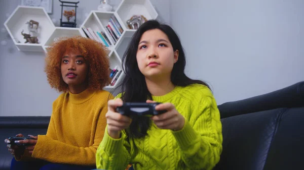 Dos mujeres jóvenes usando controlador de joystick jugando videojuegos. Competencia ganar y perder — Foto de Stock