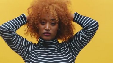 Güzel Afro-Amerikan siyah kadın yeni kıvırcık saç stilini gösteriyor.