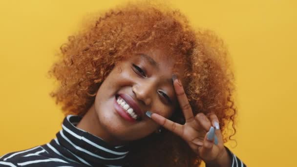Молодая африканская чёрная женщина с кудрявыми афро-волосами и длинными ногтями позирует перед жёлтым фоном. — стоковое видео