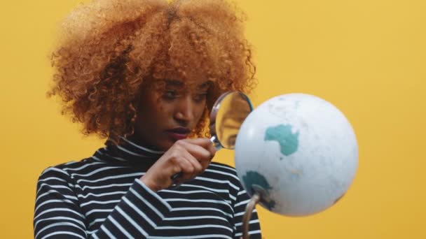 Mujer negra afroamericana joven mirando el globo a través de la lupa — Vídeos de Stock