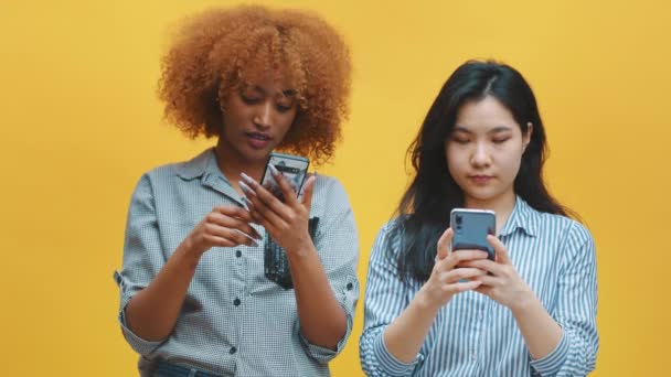 Twee jonge vrouwen controleren sociale netwerken en tonen hun verbazing met wierd gezicht uitdrukking — Stockvideo