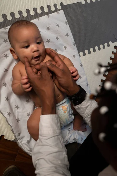 Draufsicht auf einen liebevollen jungen schwarzen Vater, der sein Mulattbaby kitzelt. Vaterschaft und multirassische Familie — Stockfoto
