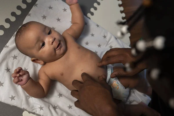 Caring young black father tickling tummy of his newborn baby . Fatherhood and multiracial family — Stock Photo, Image