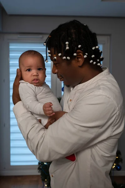 Afrika kökenli Amerikalı siyahi bir babanın melez bebeği tutarken portresi. Çok ırklı aile kavramı ve ilk bebek noeli — Stok fotoğraf