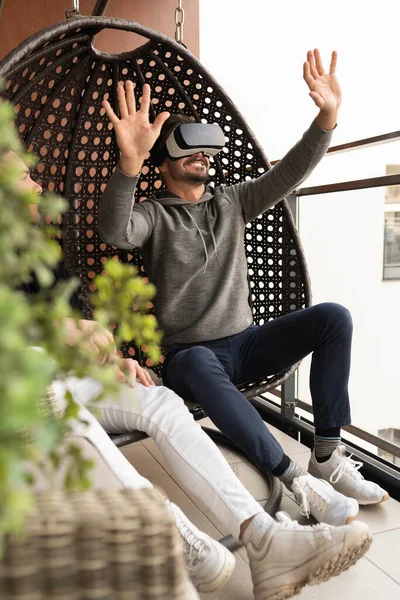 Виртуальный мир. Веселая гей-пара в VR очках веселится на балконе — стоковое фото