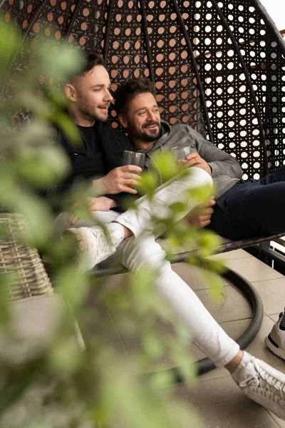 Jonge vriendjes ontspannen en drinken bier op het balkon. Liefde en genegenheid van partners van hetzelfde geslacht — Stockfoto