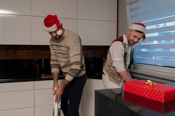 Concepto de relación homosexual. Joven pareja gay con sombreros de santa limpieza de la cocina — Foto de Stock