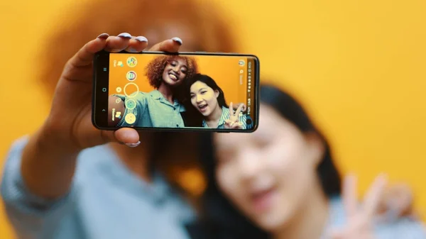 Две молодые девушки, лесбийская пара, использующая смартфон, чтобы сфотографировать. Делать гримасы — стоковое фото