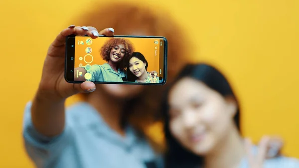 Duas jovens, melhores amigas usando smartphone para tirar fotos. Fazendo caretas — Fotografia de Stock