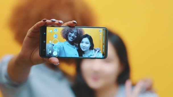 Deux jeunes filles, meilleures amies utilisant un smartphone pour prendre des photos. Faire des grimaces — Video