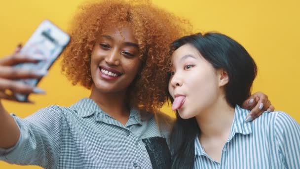 Bláznivý mladý multiracial dívka přátelé nebo lesbičky pár dělat legrační obličeje a brát selfie s smarpthone — Stock video