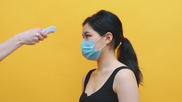 Operatore sanitario, medico controlla la temperatura della giovane donna asiatica. Test medico per la diagnosi di coronavirus in ospedale durante la pandemia. Concetto di sanità e medicina. — Video Stock