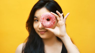 Çekici Asyalı kadın gözünün üstüne donut koyarken eğleniyor.