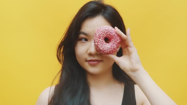 Attractive asian woman having fun Putting donuts over the eyes — Stock Video