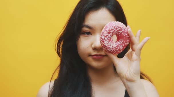 Portrait of crazy asian woman having fun Putting doughnuts over the eyes — Stock Video