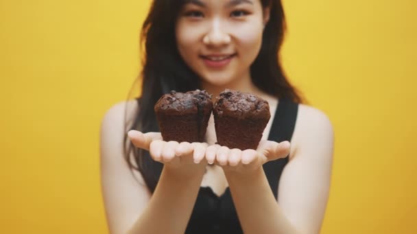 Chocolate muffins in the hands of beautiful young asian woman. Close up — Stock Video